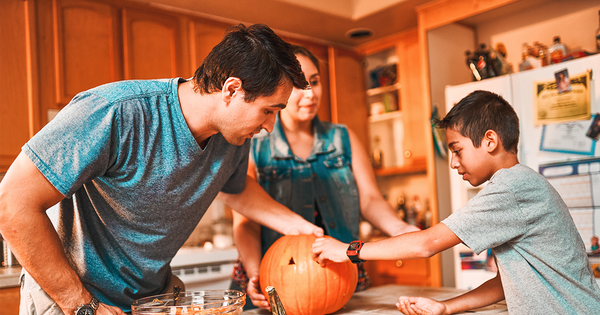 family carving a pumpkin in the kitchen