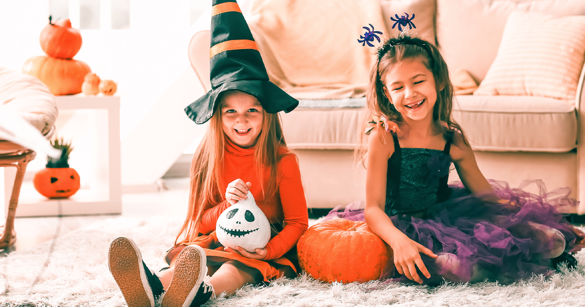 little girls in halloween costumes at home sitting on the floor