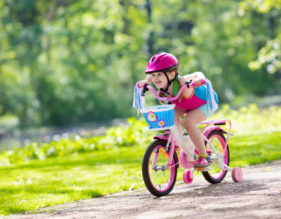 Child riding a bike with a helmet and backpack on heading home from school